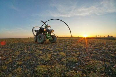 Bicycle on field against sky during sunset