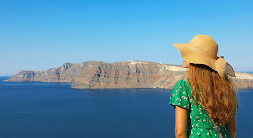 Rear view of man looking at sea against clear blue sky