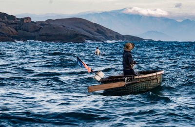 Men on boat in sea against sky