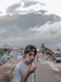 Young man smoking cigarette while standing on road