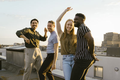 Group of happy male and female having fun while dancing on building terrace