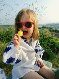 Cute girl eating lollipop while sitting on bench