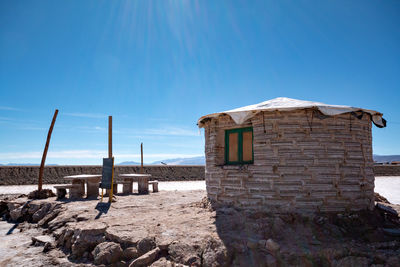 Old house on beach against clear blue sky