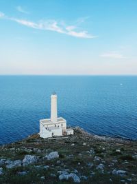 Lighthouse amidst sea and buildings against sky