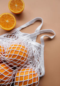 Eco-friendly bag with ripe oranges on brown background