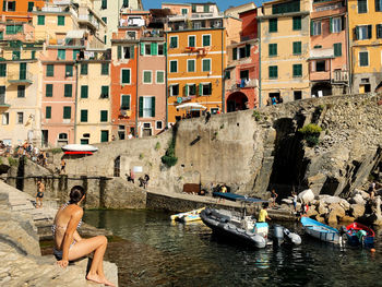 People on boats in canal against buildings in city