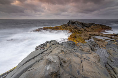 Rock formations on shore against sky