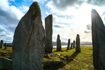 Rocks on field at hebrides against sky