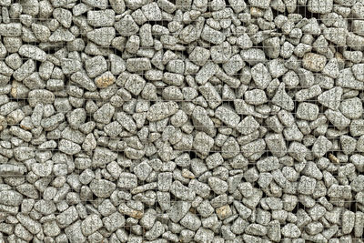 Textured background of a stone wall with iron netting. stone wall in wire frame.