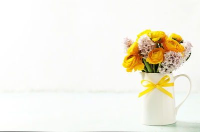 Close-up of yellow flower vase against white background