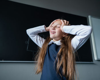 Portrait of young woman standing against wall