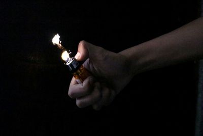 Man holding illuminated lamp over black background