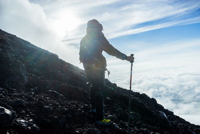 Low angle view of hiker standing on mountain against sky