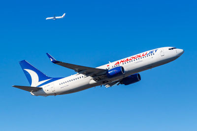 Low angle view of airplane flying against clear blue sky