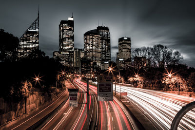 Light trails on road in city against sky at night