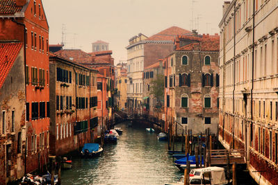 Narrow canal with boats between old houses in venice, italy