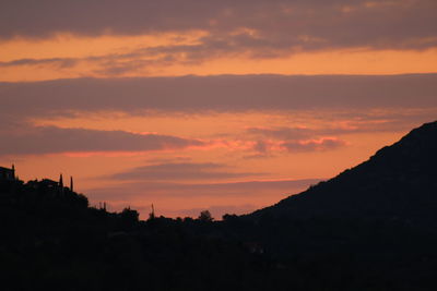 Silhouette landscape against dramatic sky during sunset