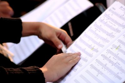 Cropped image of hands on music sheet