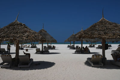 Lounge chairs and parasols on beach against clear sky