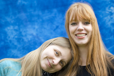 Close-up portrait of happy mother and daughter against blue sky