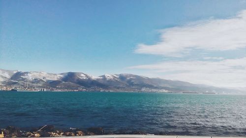 Scenic view of sea and mountains against blue sky