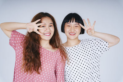 Portrait of happy lesbian couple against gray background