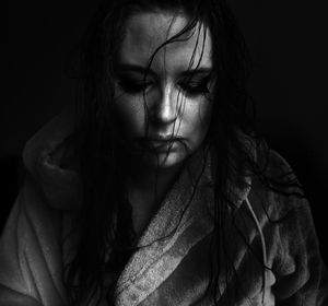 Sad woman in bathrobe against black background