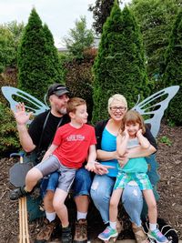 Happy family sitting against tree