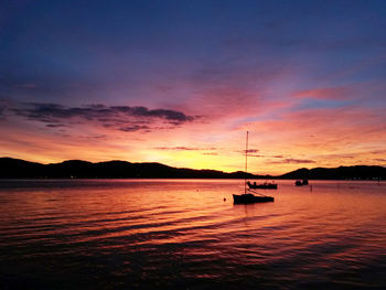 Silhouette boat sailing in sea against sky during sunset