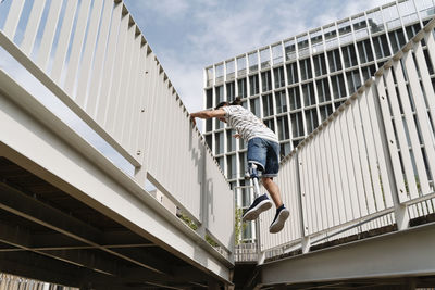 Amputed man against bridge railing in city