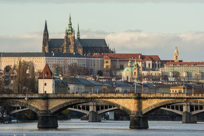 Arch bridge over river against buildings in city