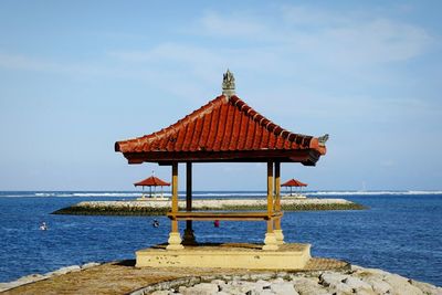 Gazeboes in sea against sky