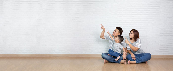 Friends sitting on floor against wall