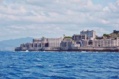 Sea by buildings against sky in city