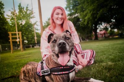 Portrait of dog with owner sitting on grass at park