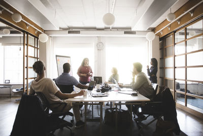 Businesswoman discussing business strategy with coworkers in meeting at board room