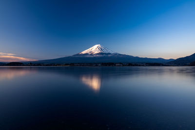 Scenic view of lake and snowcapped mountains against blue sky