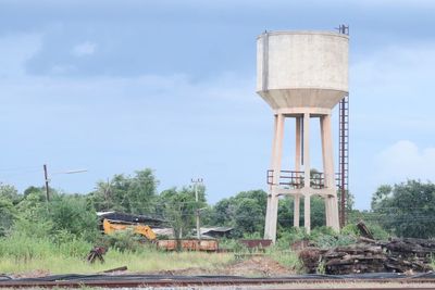 Old water tower on land against sky