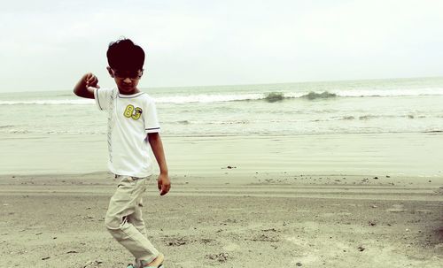 Boy playing on beach against sky