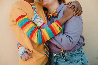 Loving multiethnic lesbian couple in rainbow accessories hugging tenderly