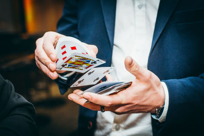 Midsection of man gambling playing cards in casino