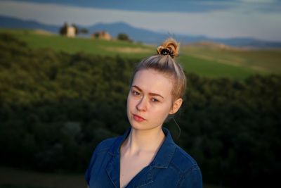 Close-up portrait of young woman against field