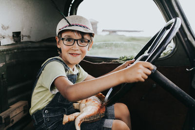 Portrait of boy holding steering wheel sitting in car