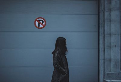 Young woman standing against wall