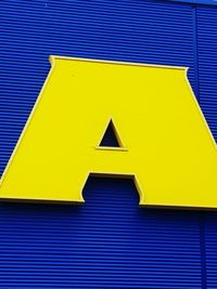 Low angle view of yellow sign on wall