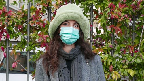 Portrait of young woman standing against plants