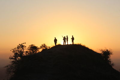 Silhouette people standing by tree against sky during sunset