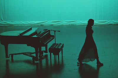 High angle view of pianist woman walking by piano on stage