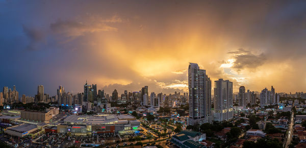 Modern buildings in city against sky during sunset