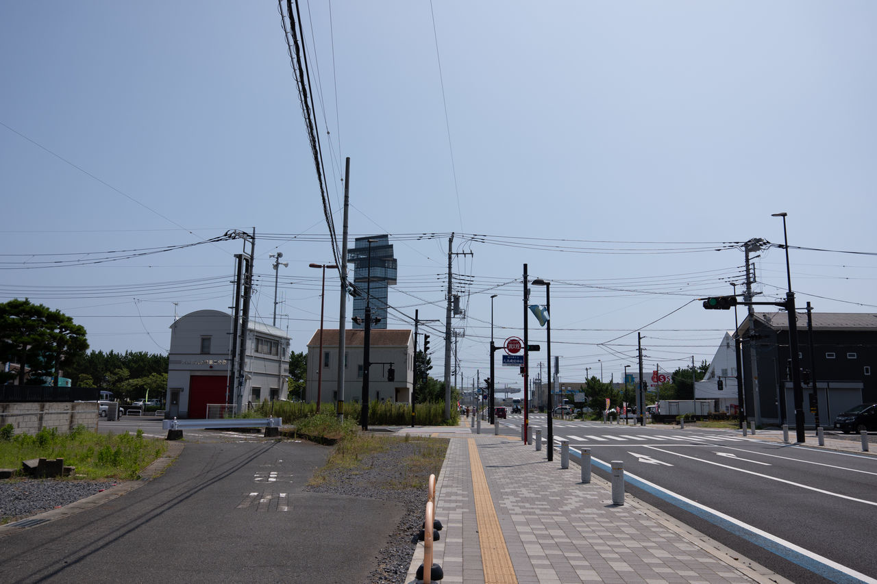 STREET BY ELECTRICITY PYLON AGAINST SKY